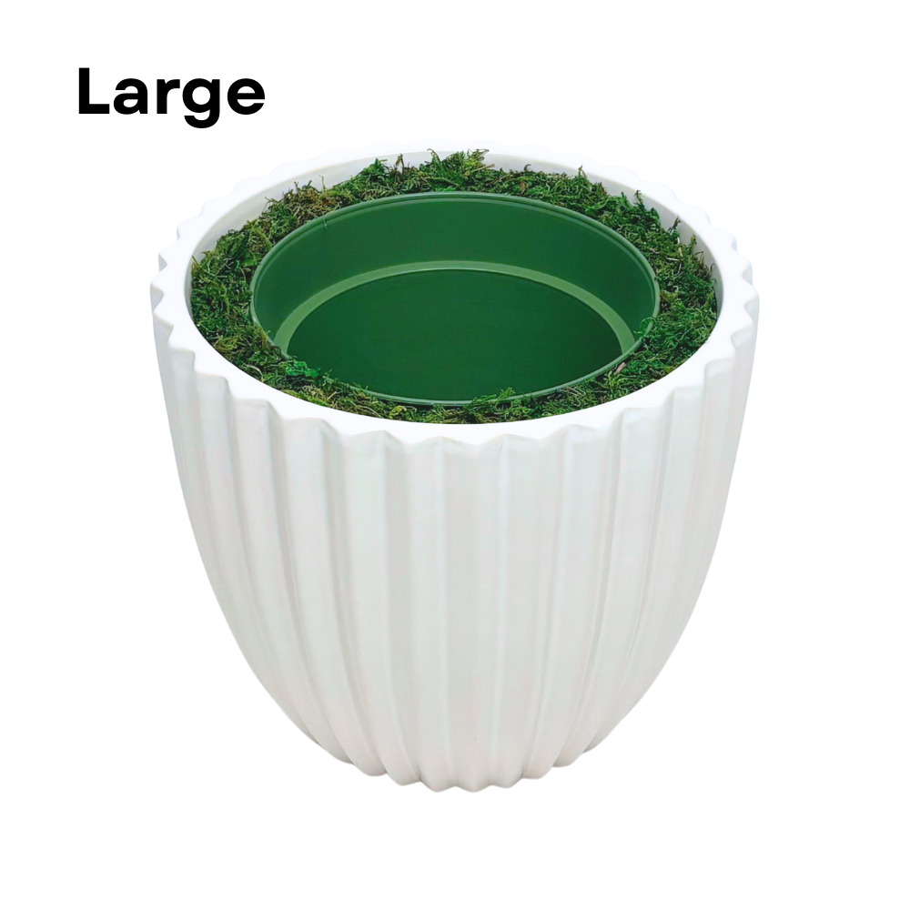 Image of a large glossy white ribbed ceramic container, containing faux moss and a green nursery pot, shown as House of Silk Flowers' pot-in-a-pot system.