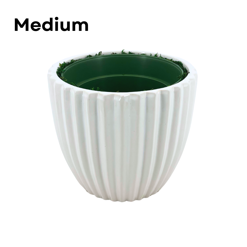 Image of a medium glossy white ribbed ceramic container, containing faux moss and a green nursery pot, shown as House of Silk Flowers' pot-in-a-pot system.