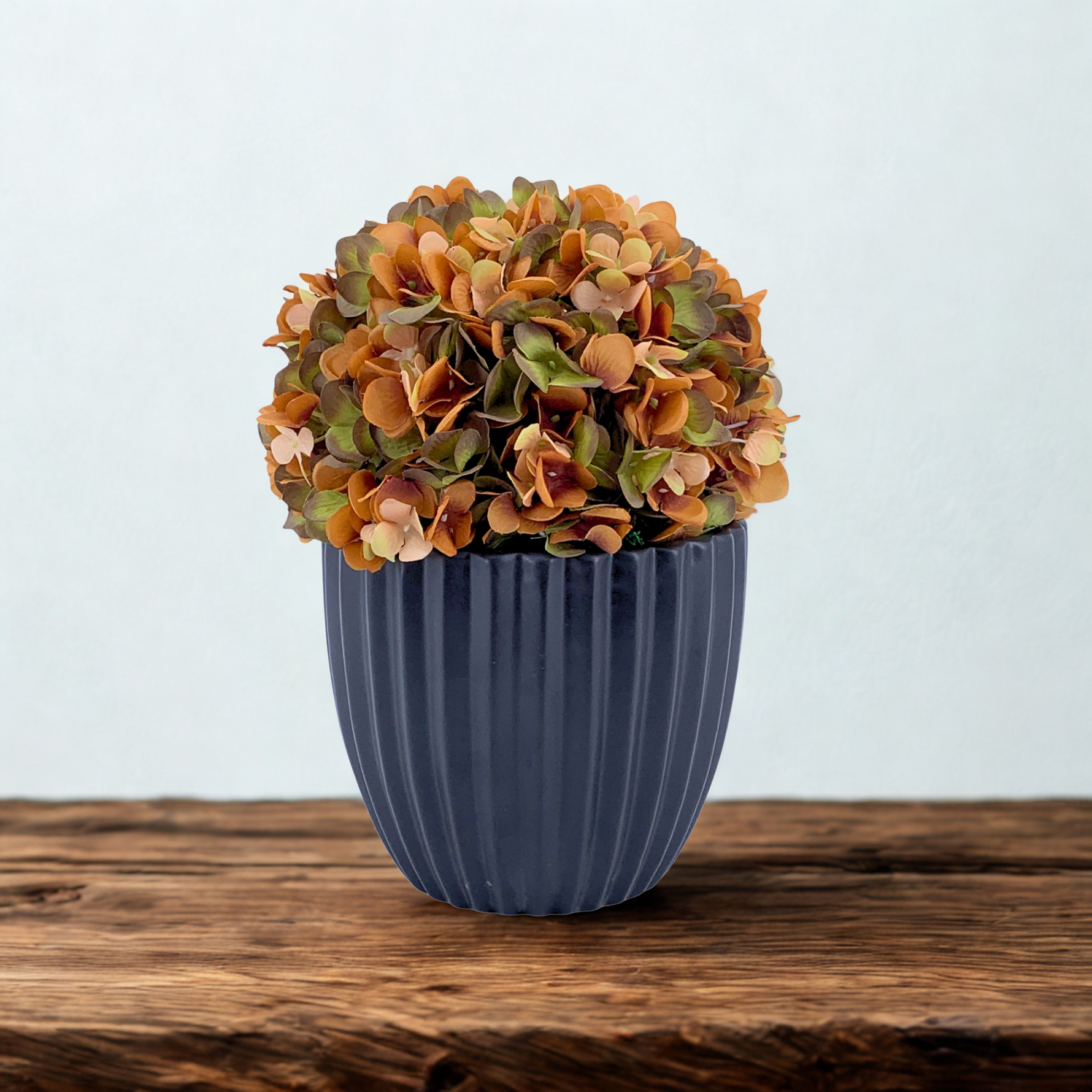 Artificial hydrangea with autumnal colors in a Matte Black Ribbed Ceramic, sitting on a wooden counter with a white background, by House of Silk Flowers 