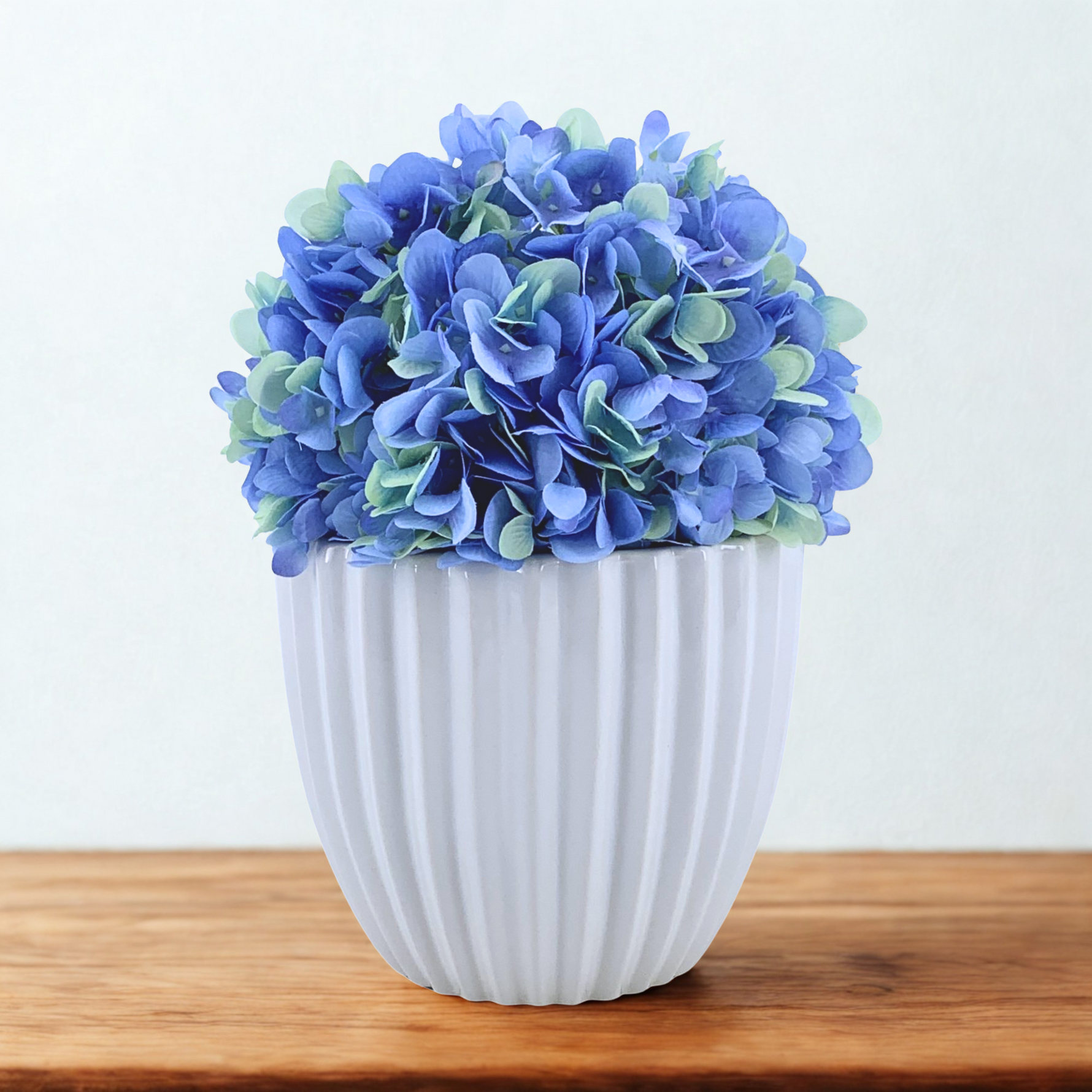 Artificial Hydrangea in Blue in a Glossy White Ceramic, on a wood counter on a white background, by House of Silk Flowers 