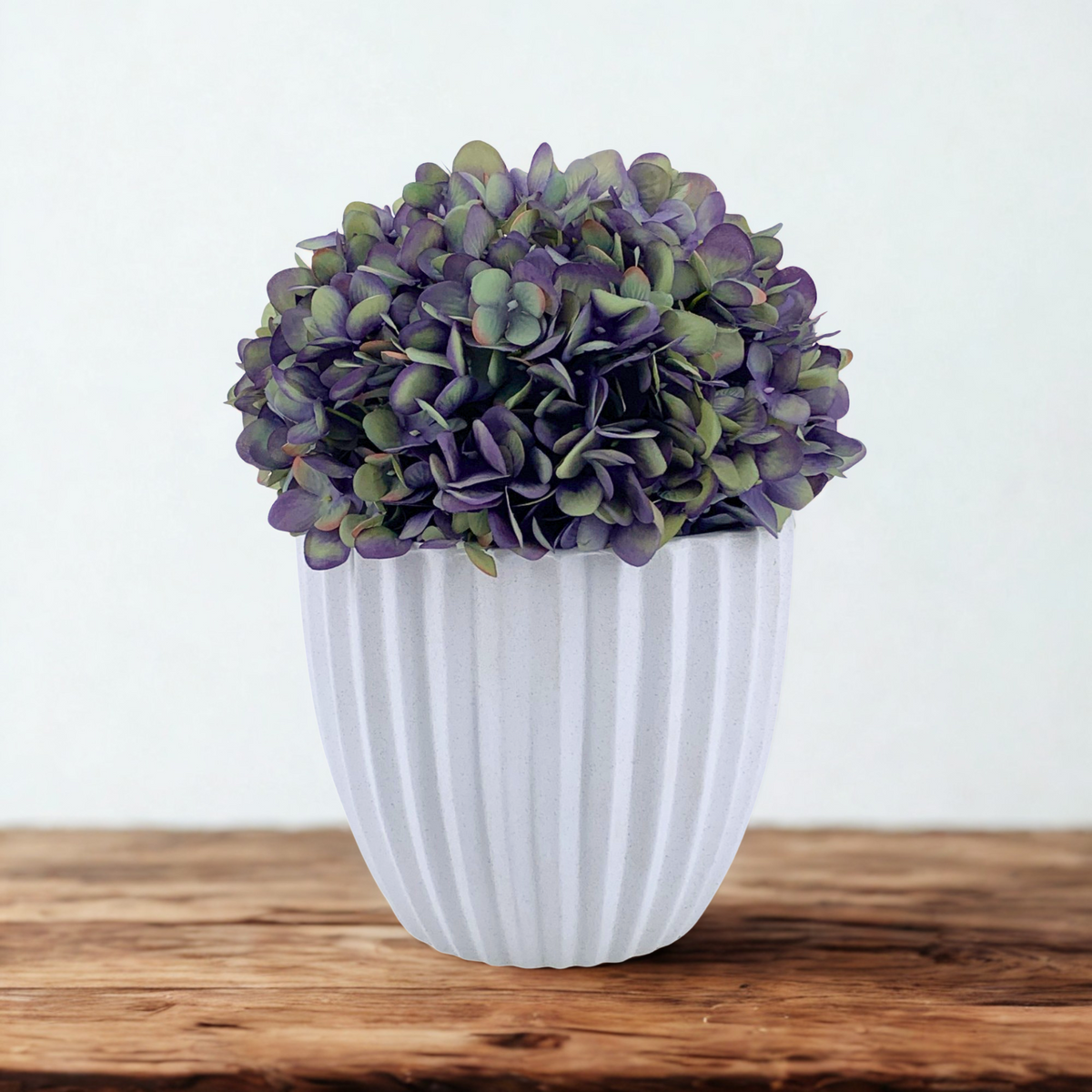 Artificial Hydrangea in Mauve in a Stone White Ceramic, sitting on a wood countertop on a white background by House of Silk Flowers 