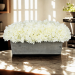 White hydrangeas in a grey wooden planter in a kitchen environment